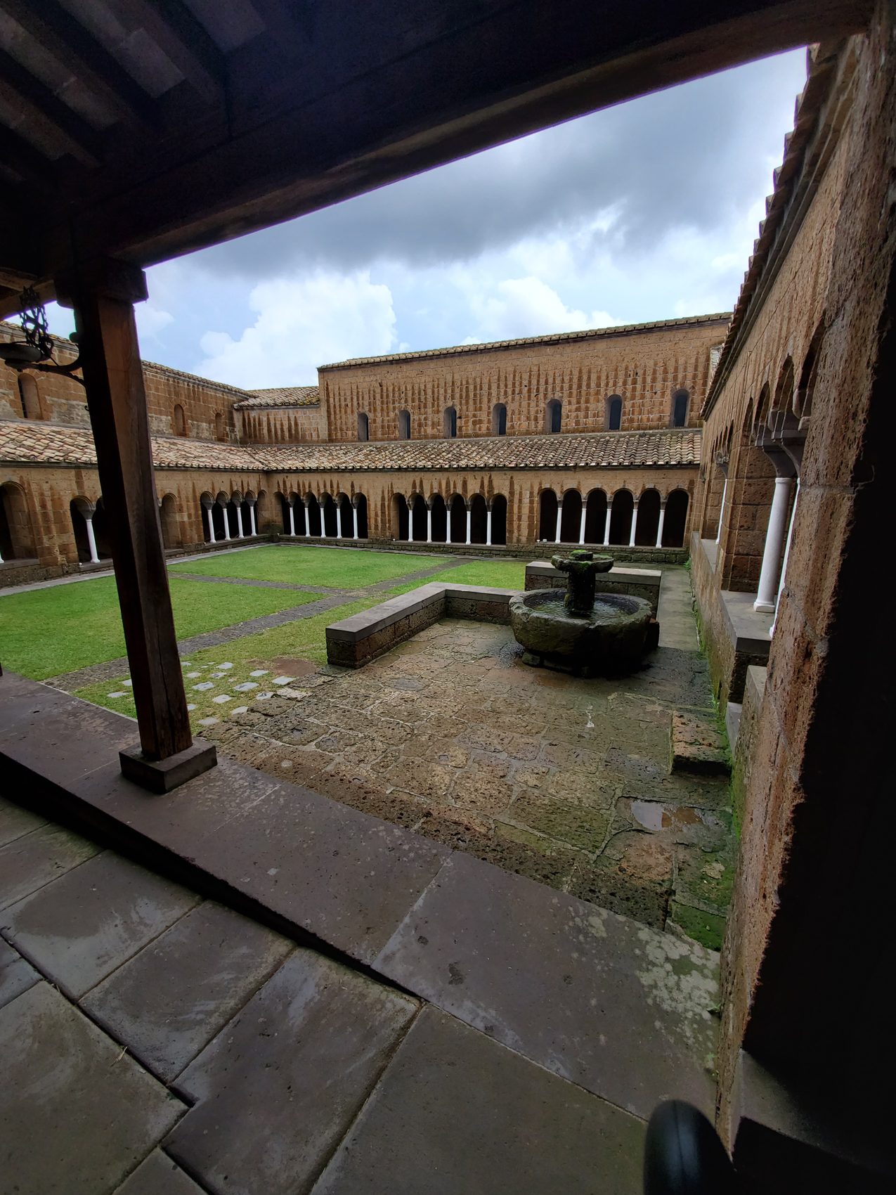 The cloister and its ancient stone fountain, seen from the covered walkway.